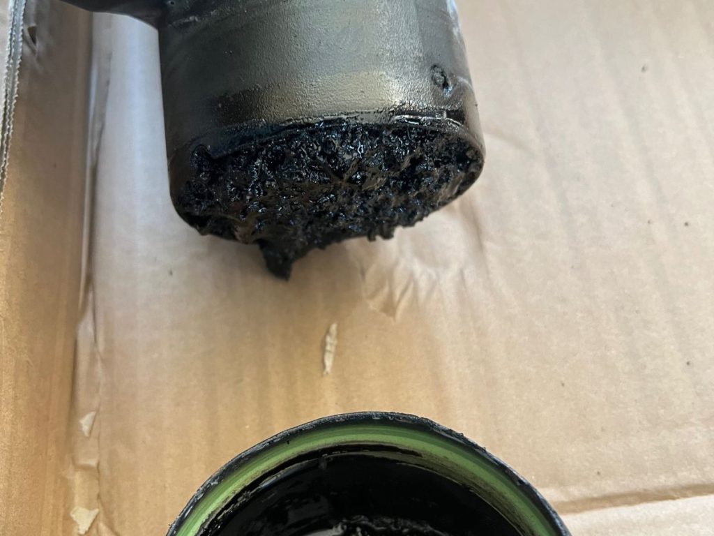 Accumulation de bistre dans un té de conduit de cheminée, point bas favorisant la condensation des fumées.